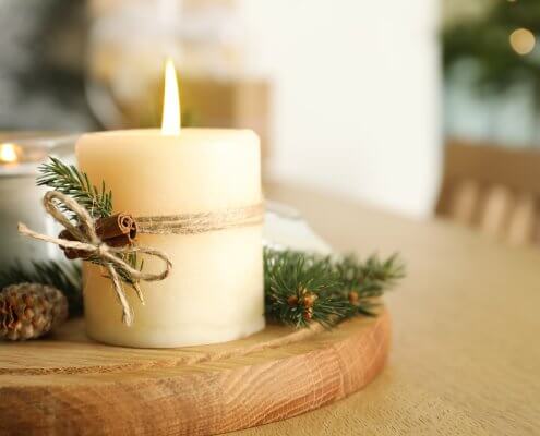 Brennende duftende Nadelkerzen und Weihnachtsdekor auf Holztisch