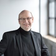 Claus Goerner, CEO von UID, in dunklem Anzug und dunklem Rollkragenpullover